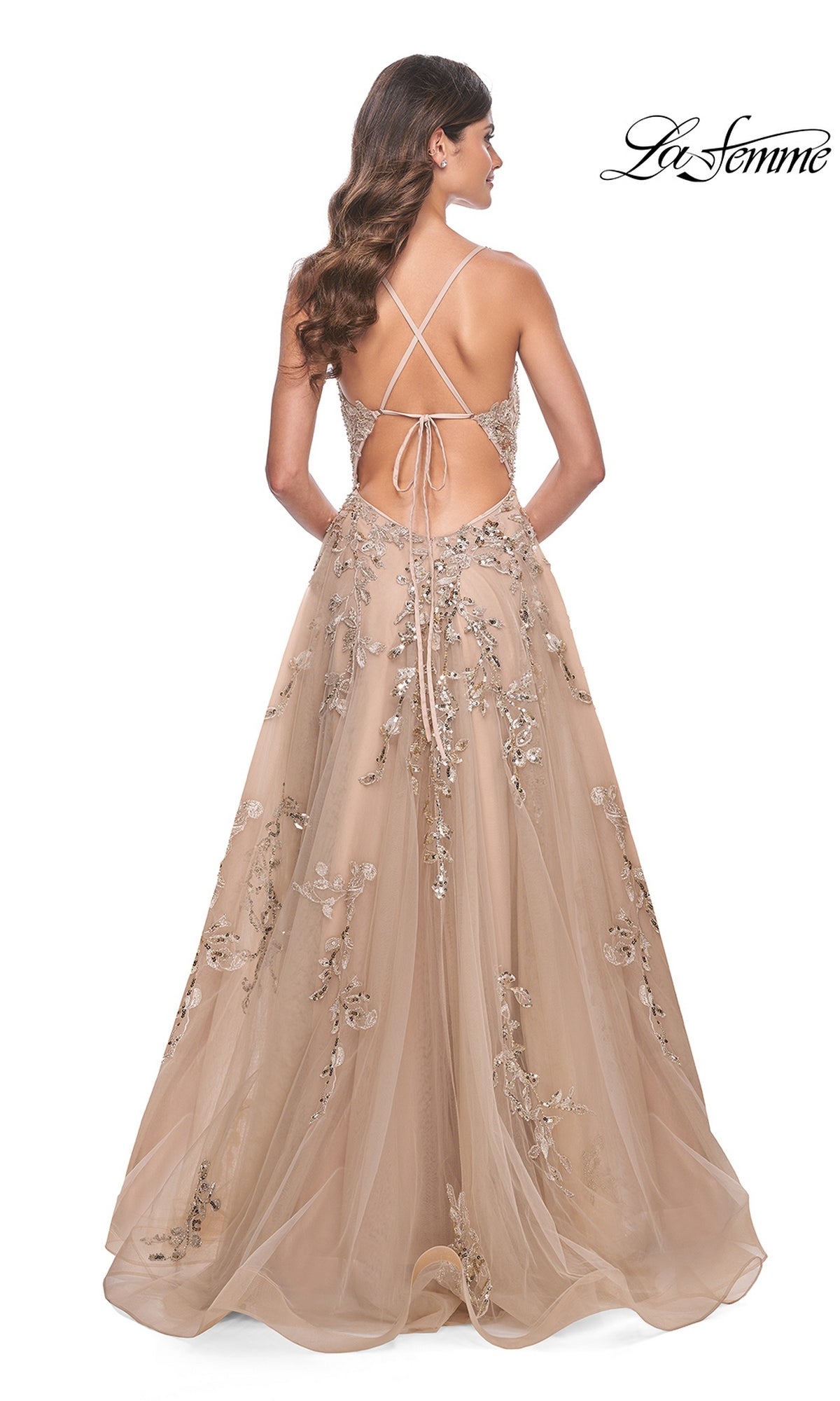 A woman is seen from behind in the La Femme Sheer-Bodice Long Lace Prom Dress 32052, a floor-length gown with silver floral embellishments, thin crisscross straps, and a backless design.